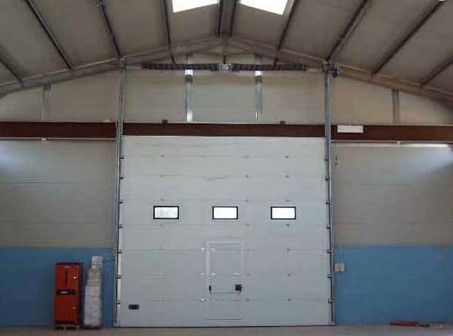 portone sezionale industriale acciaio coibentato con oblò e porta pedonale antipanico