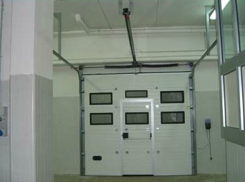 portone sezionale industriale acciaio coibentato con oblò e porta pedonale antipanico